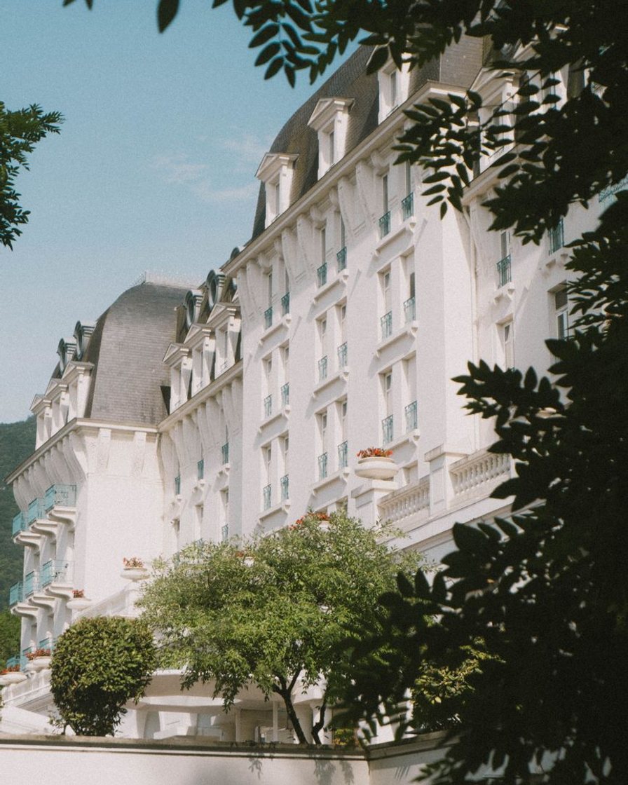 Chambre d'hôtel vue depuis la porte, lit fait et fenêtre à volets ouverte sur le lac d'Annecy
